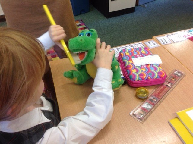 Child learning how to brush teeth on dinosaur plush toy during a school talk by Dr Moira Wong